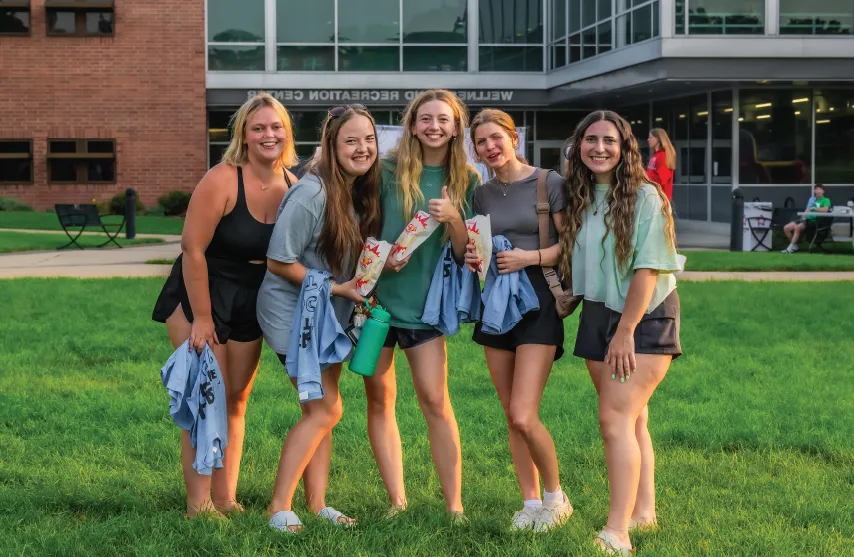 A group of students smiling outdoors in front of the Wellness and Recreation Center.